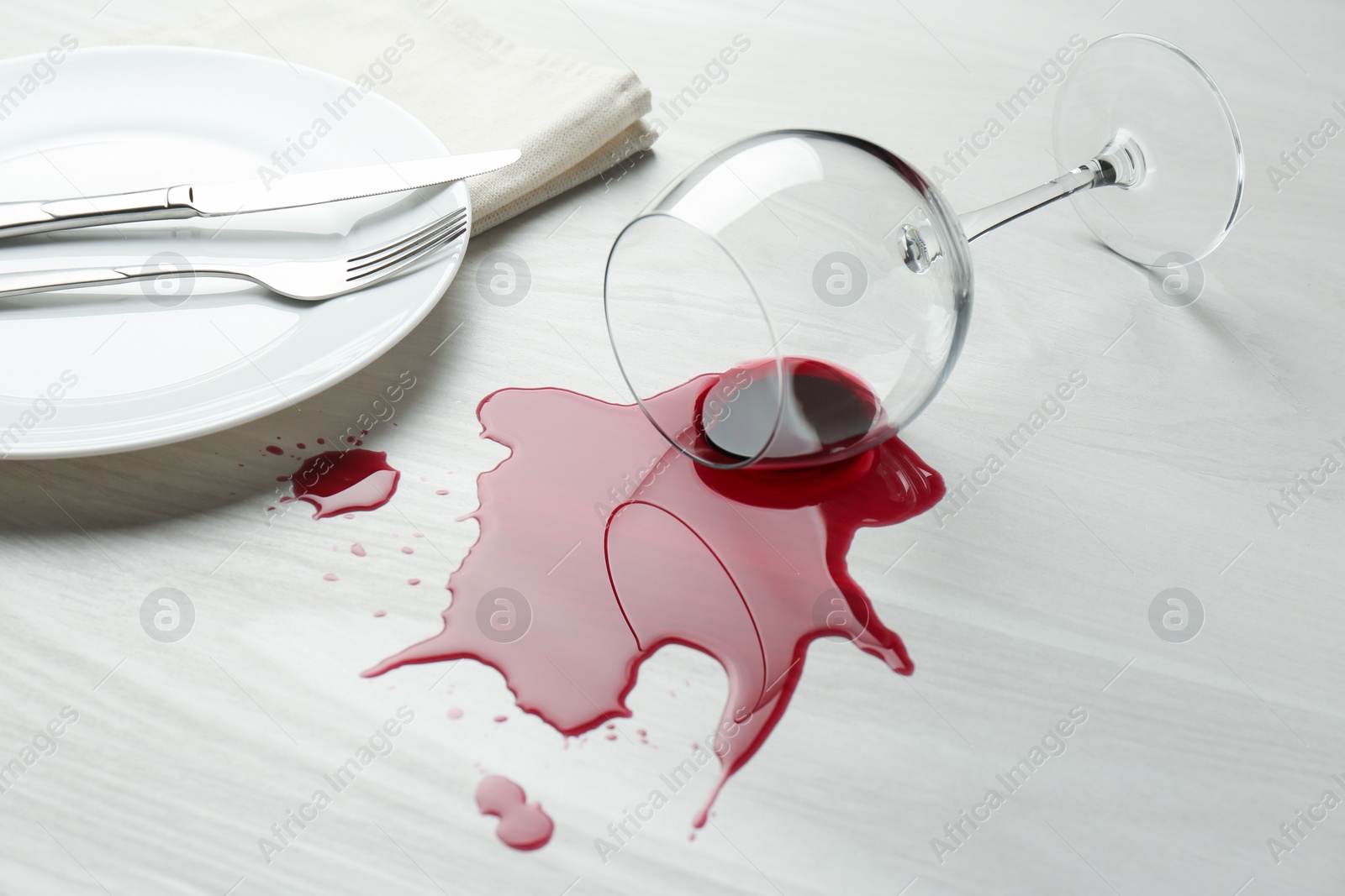 Photo of Overturned glass and spilled wine on white wooden table