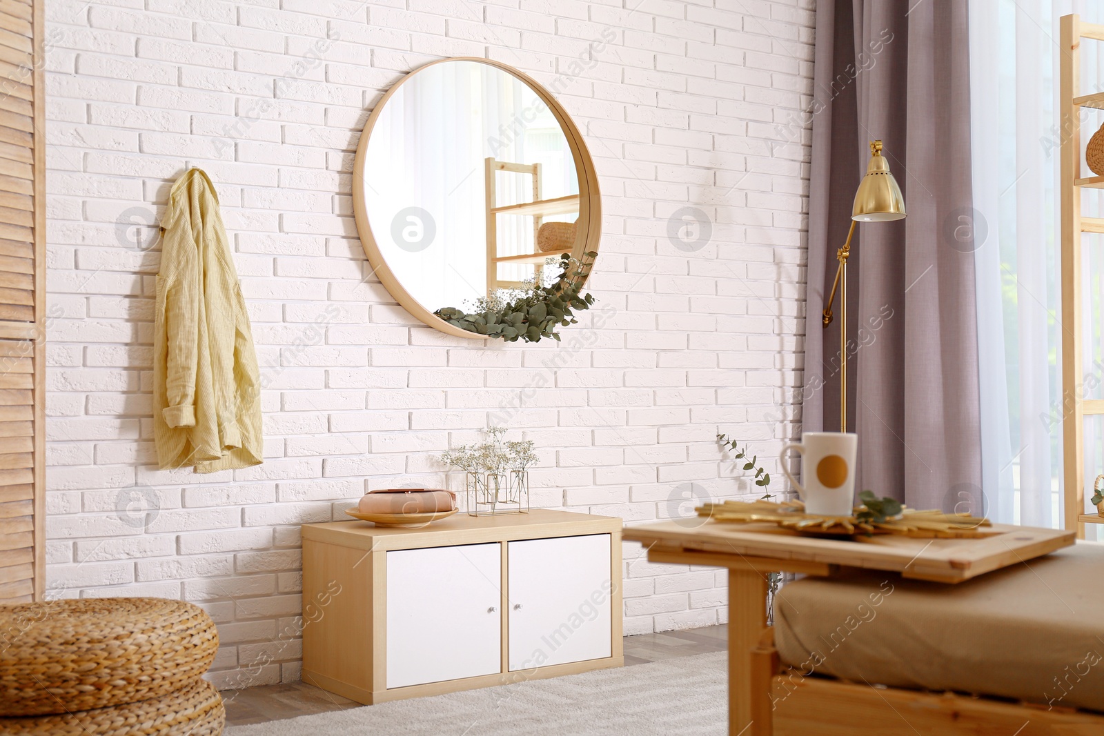 Photo of Elegant room interior with round mirror on brick wall