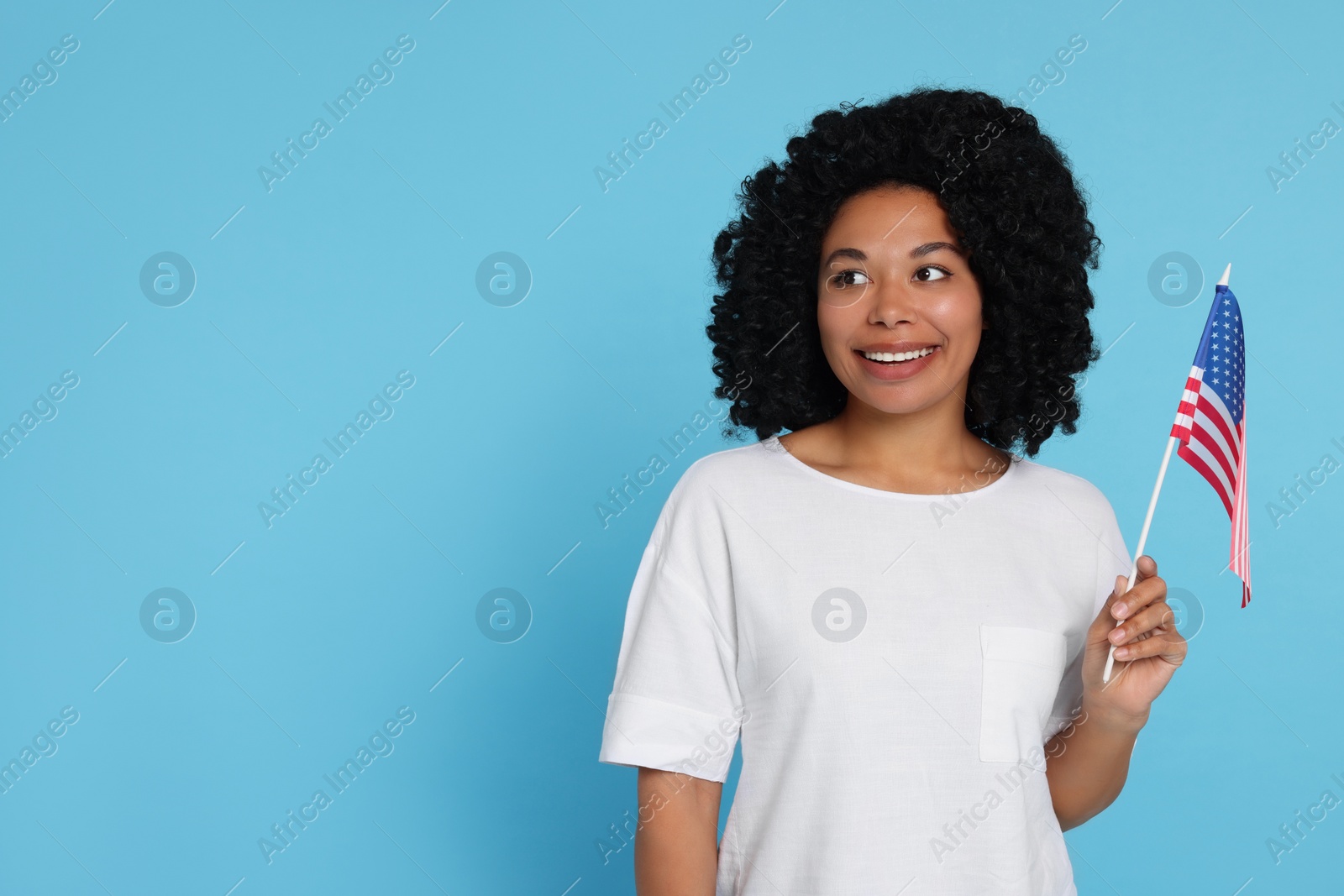 Photo of 4th of July - Independence Day of USA. Happy woman with American flag on light blue background, space for text