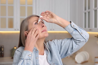 Woman applying medical eye drops at home