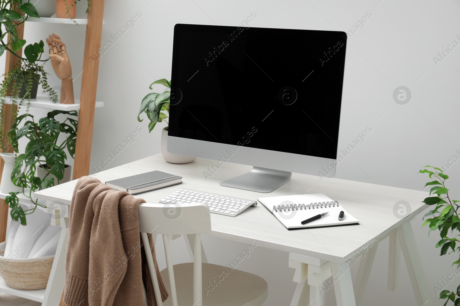 Photo of Spacious workspace with desk, chair, computer and potted plants at home