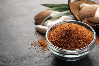 Natural coconut sugar in glass bowl on black table. space for text