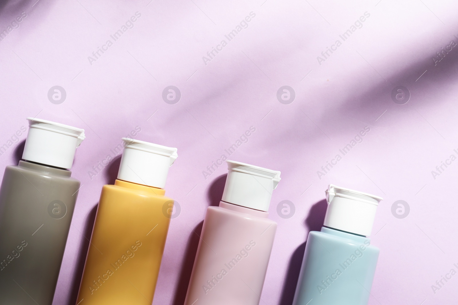 Photo of Cosmetic travel kit on violet background, top view. Space for text