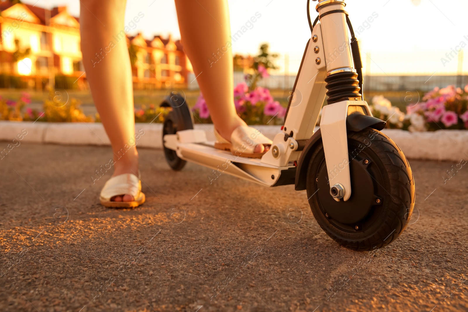 Photo of Woman riding electric kick scooter outdoors on sunny day, closeup