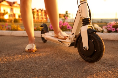 Woman riding electric kick scooter outdoors on sunny day, closeup