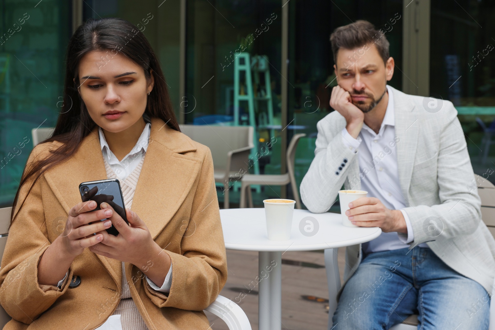 Photo of Upset arguing couple in outdoor cafe. Relationship problems