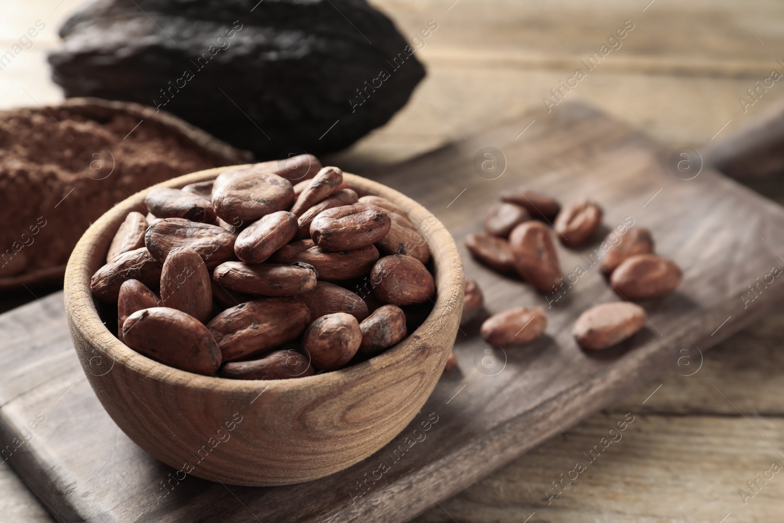 Photo of Bowl with cocoa beans on wooden table, space for text