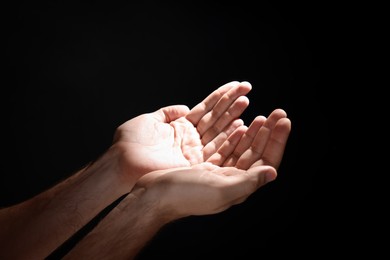 Photo of Man reaching hands to light in darkness, closeup