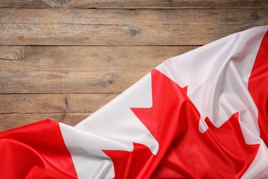 Flag of Canada on wooden background, top view. Space for text