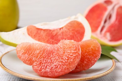 Tasty pomelo fruits on white wooden table, closeup