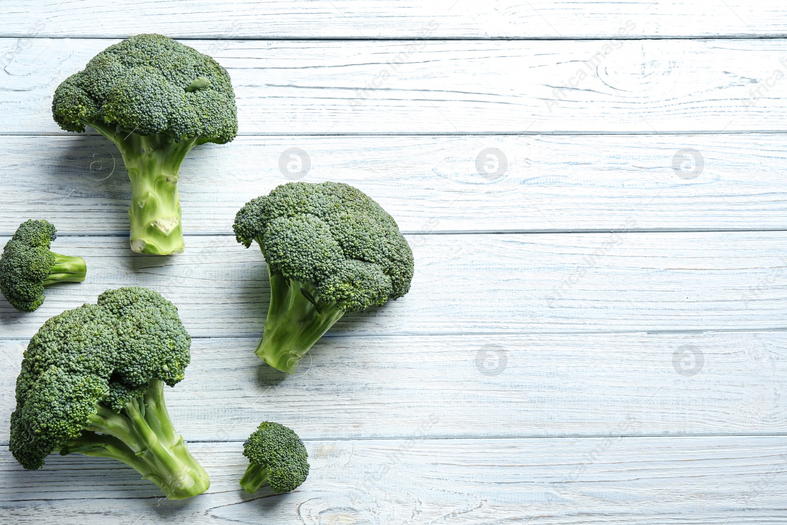 Photo of Fresh green broccoli on white wooden table, flat lay. Space for text