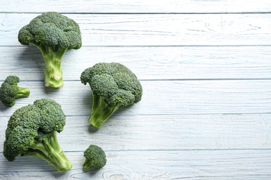 Photo of Fresh green broccoli on white wooden table, flat lay. Space for text