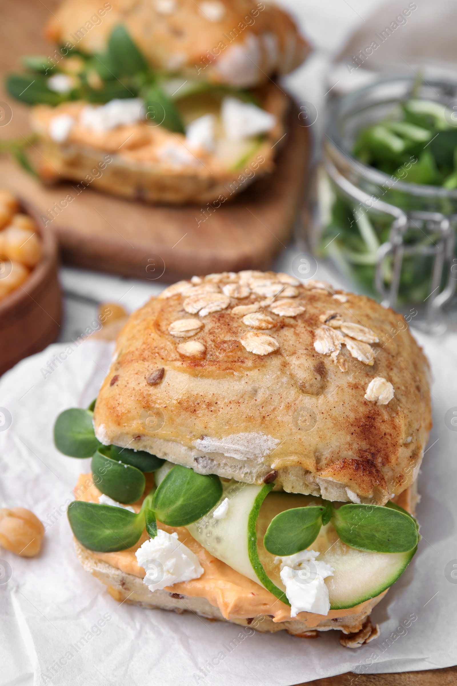 Photo of Delicious sandwich with hummus, microgreens and cucumber slices on white table, closeup