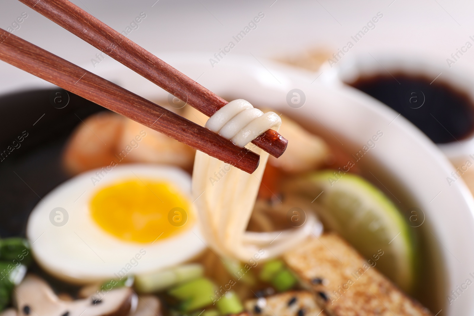 Photo of Eating delicious ramen with chopsticks, closeup. Noodle soup