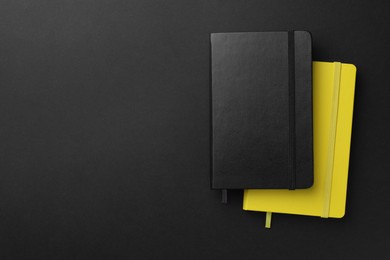 Different notebooks on black background, top view. Space for text