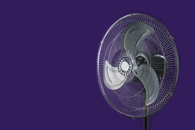 Photo of Modern electric fan on violet background. Space for text