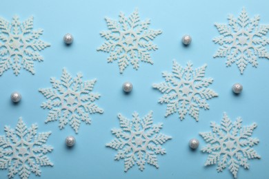 Photo of Beautiful snowflakes and decorative balls on light blue background, flat lay