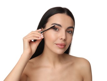 Beautiful young woman applying mascara on white background