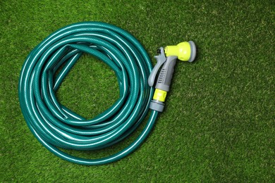 Watering hose with sprinkler on green grass, top view