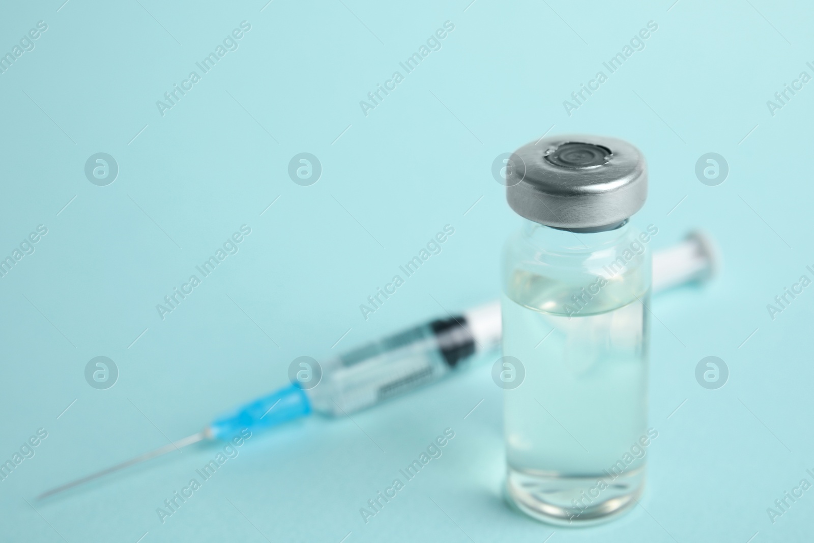 Photo of Vial and syringe on turquoise  background, space for text. Vaccination and immunization