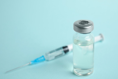 Vial and syringe on turquoise  background, space for text. Vaccination and immunization