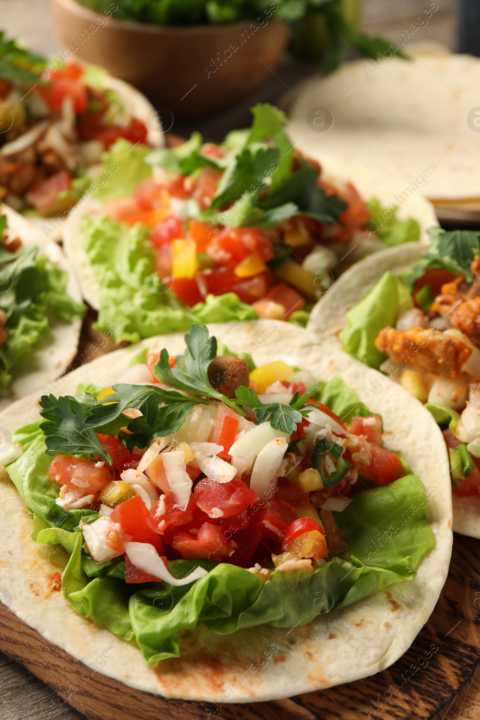 Photo of Delicious tacos with vegetables and meat on table, closeup