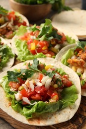 Delicious tacos with vegetables and meat on table, closeup