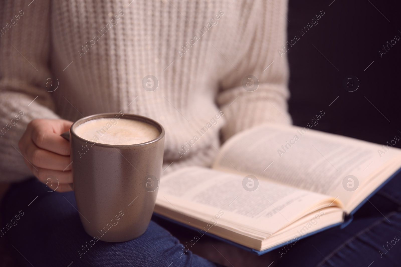 Photo of Woman with cup of coffee reading book at home, closeup