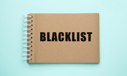 Image of Word Blacklist written in notepad on light blue background, top view