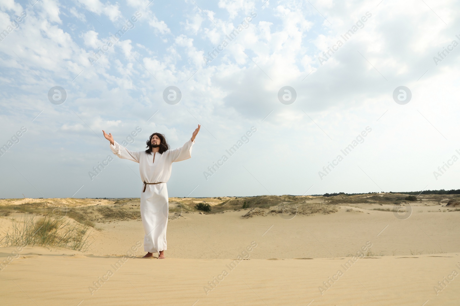 Photo of Jesus Christ raising hands in desert. Space for text