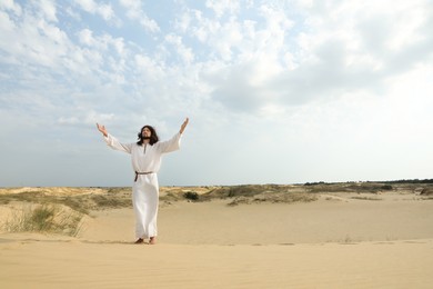 Photo of Jesus Christ raising hands in desert. Space for text