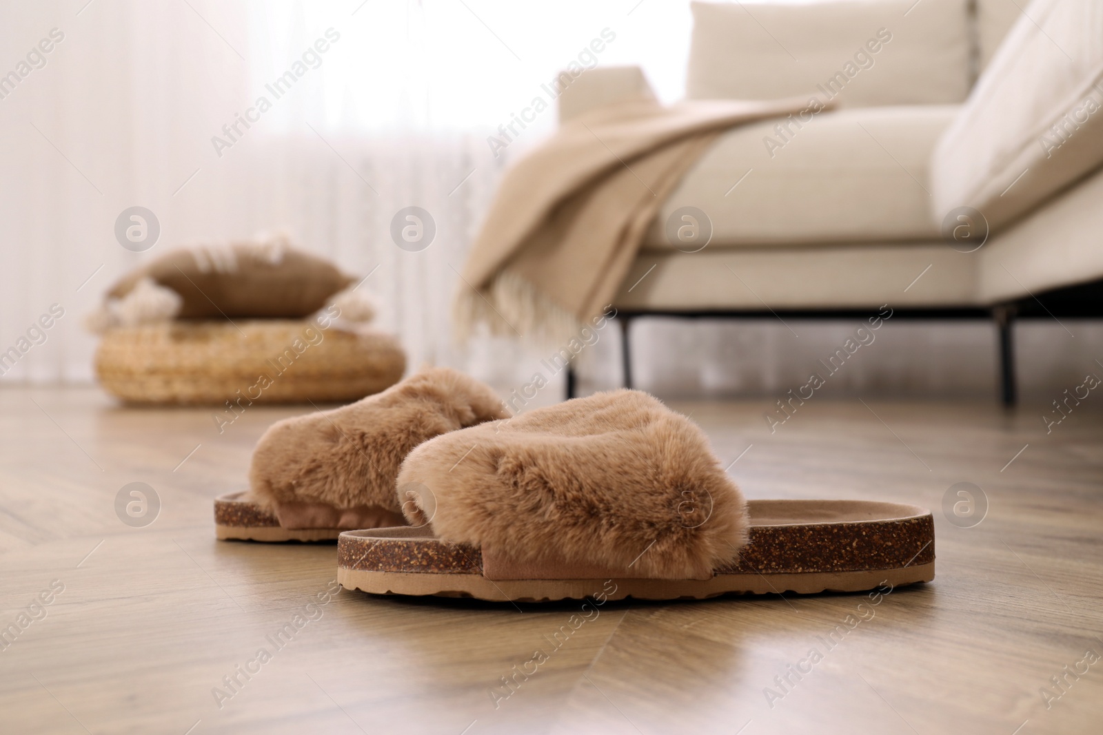 Photo of Pair of brown soft slippers on wooden floor in room