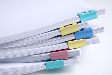 Photo of Many sheets of paper with colorful clips on white background, closeup