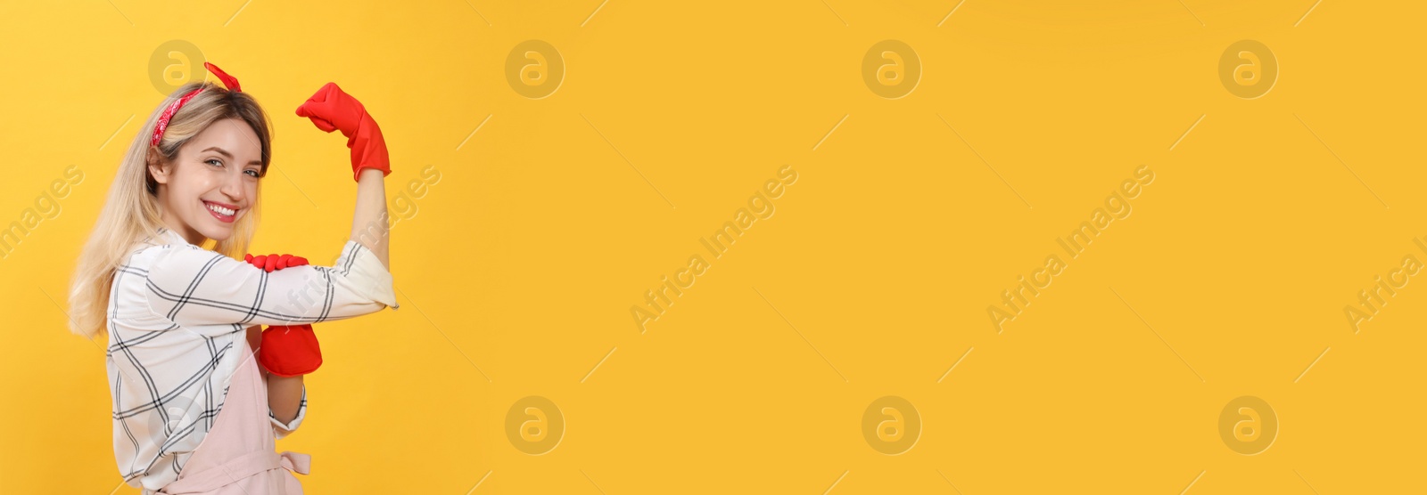 Photo of Young housewife in gloves on yellow background. Space for text