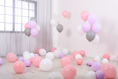 Room decorated with colorful balloons near wall