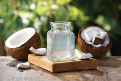 Photo of Coconut oil on wooden table against blurred background