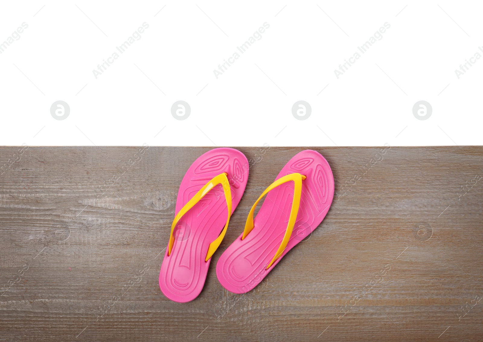 Photo of Pink flip flops on wooden table against white background, top view