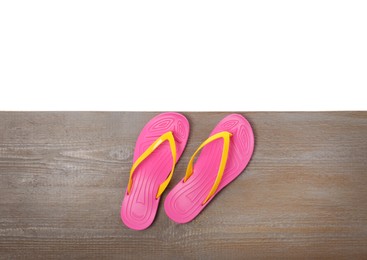 Photo of Pink flip flops on wooden table against white background, top view