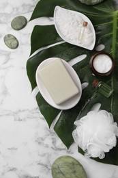 Flat lay composition with different spa products and tropical leaf on white marble table