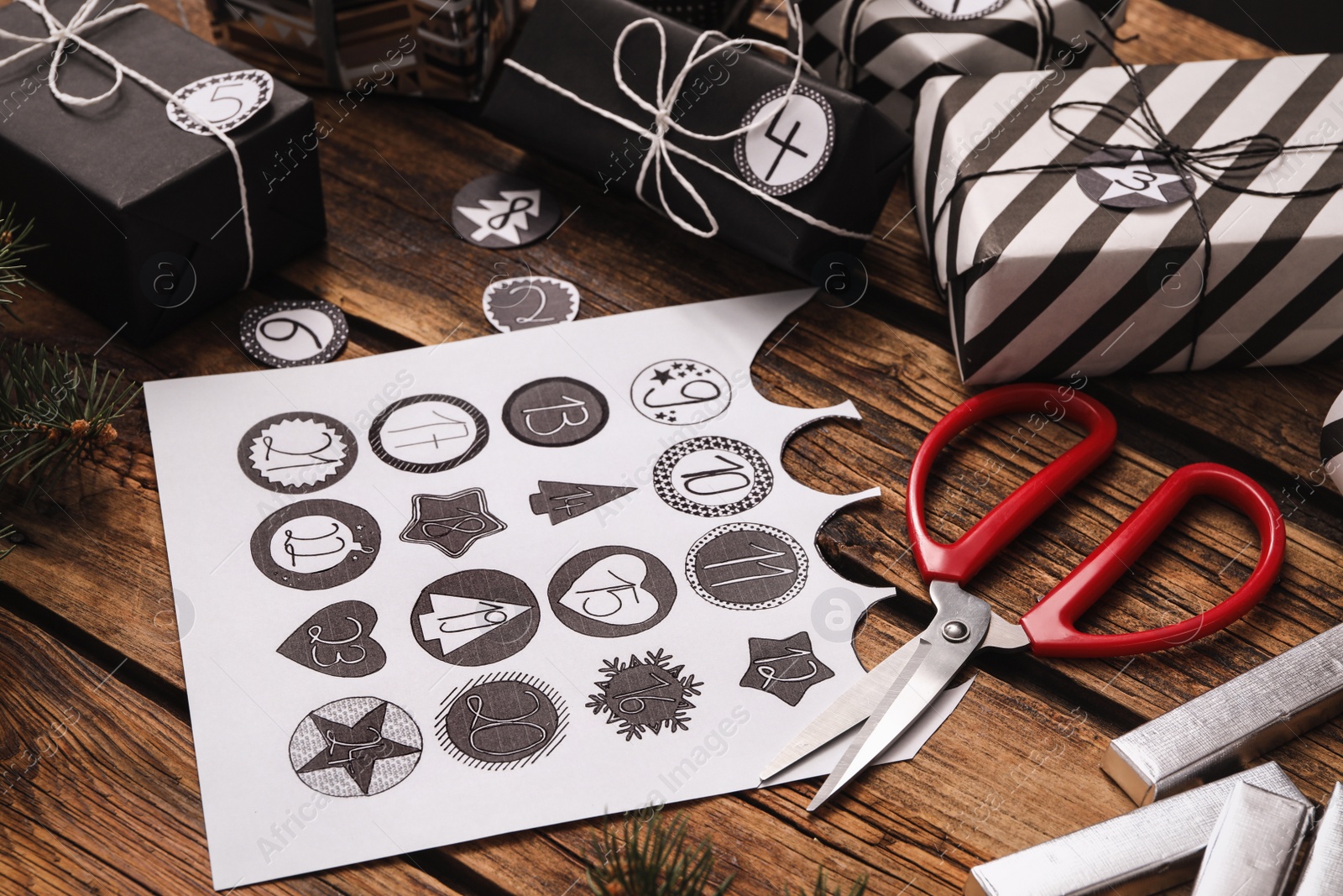 Photo of Gift boxes, scissors and sheet of paper on wooden table, closeup. Creating advent calendar