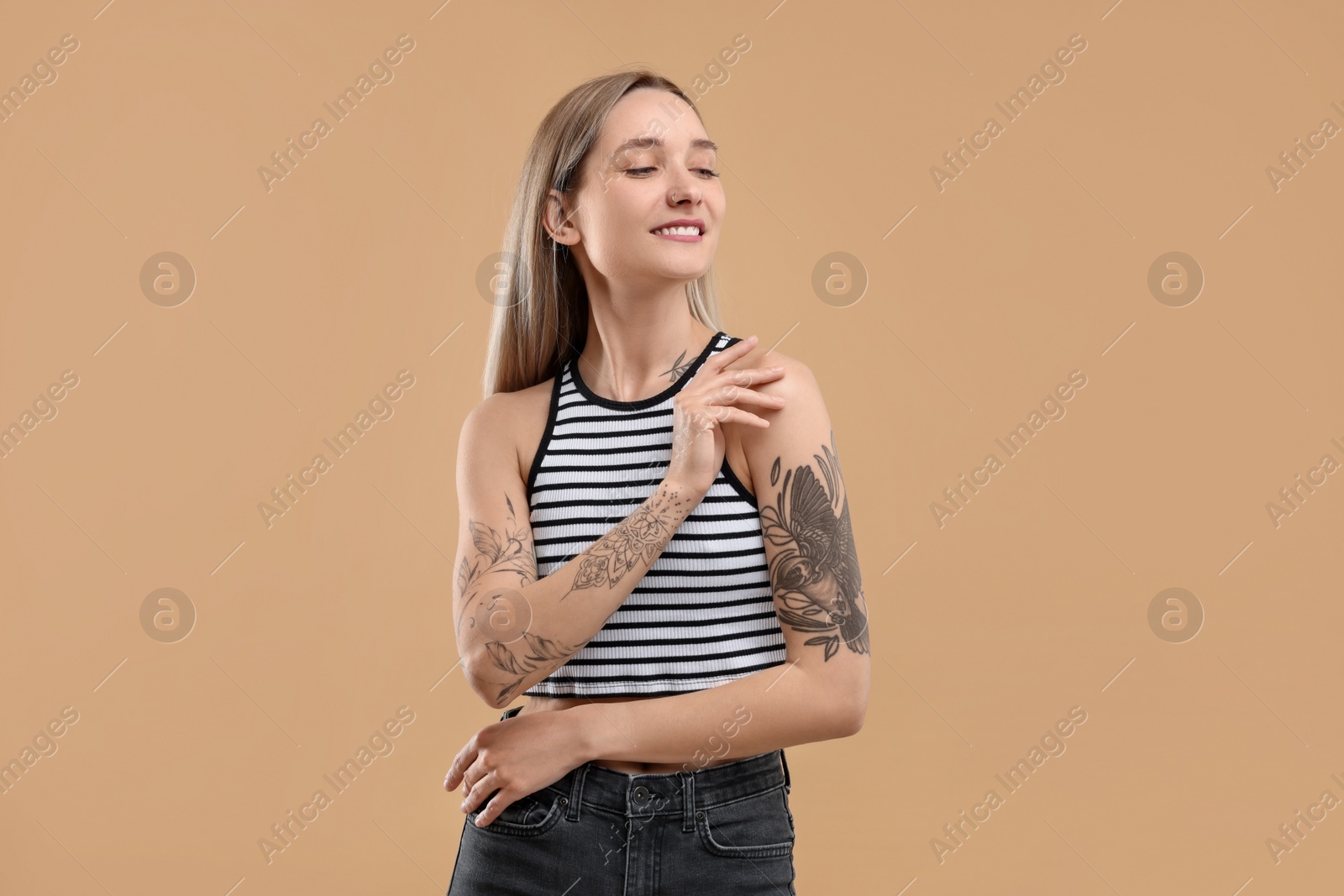 Photo of Portrait of beautiful tattooed woman on beige background