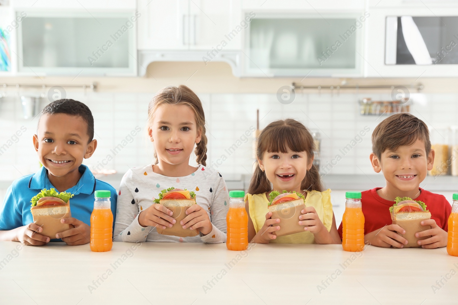 Photo of Children sitting at table and eating healthy food during break at school