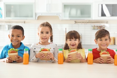 Children sitting at table and eating healthy food during break at school