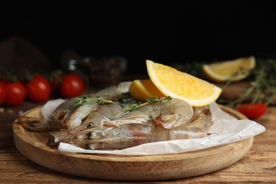 Photo of Fresh raw shrimps with lemon slices on wooden table