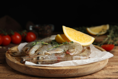 Fresh raw shrimps with lemon slices on wooden table