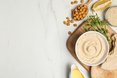Delicious hummus and different ingredients on white marble table, flat lay. Space for text
