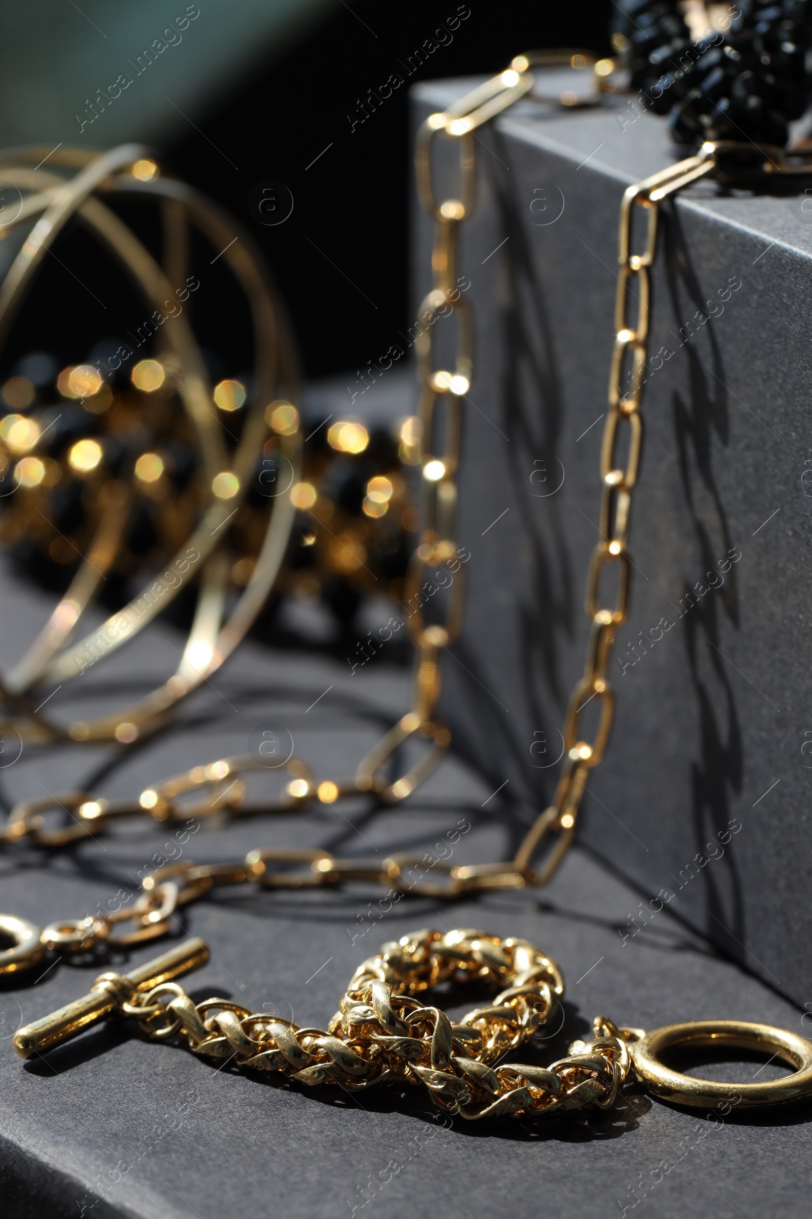 Photo of Presentation of metal chains and other different accessories on black table, closeup. Luxury jewelry