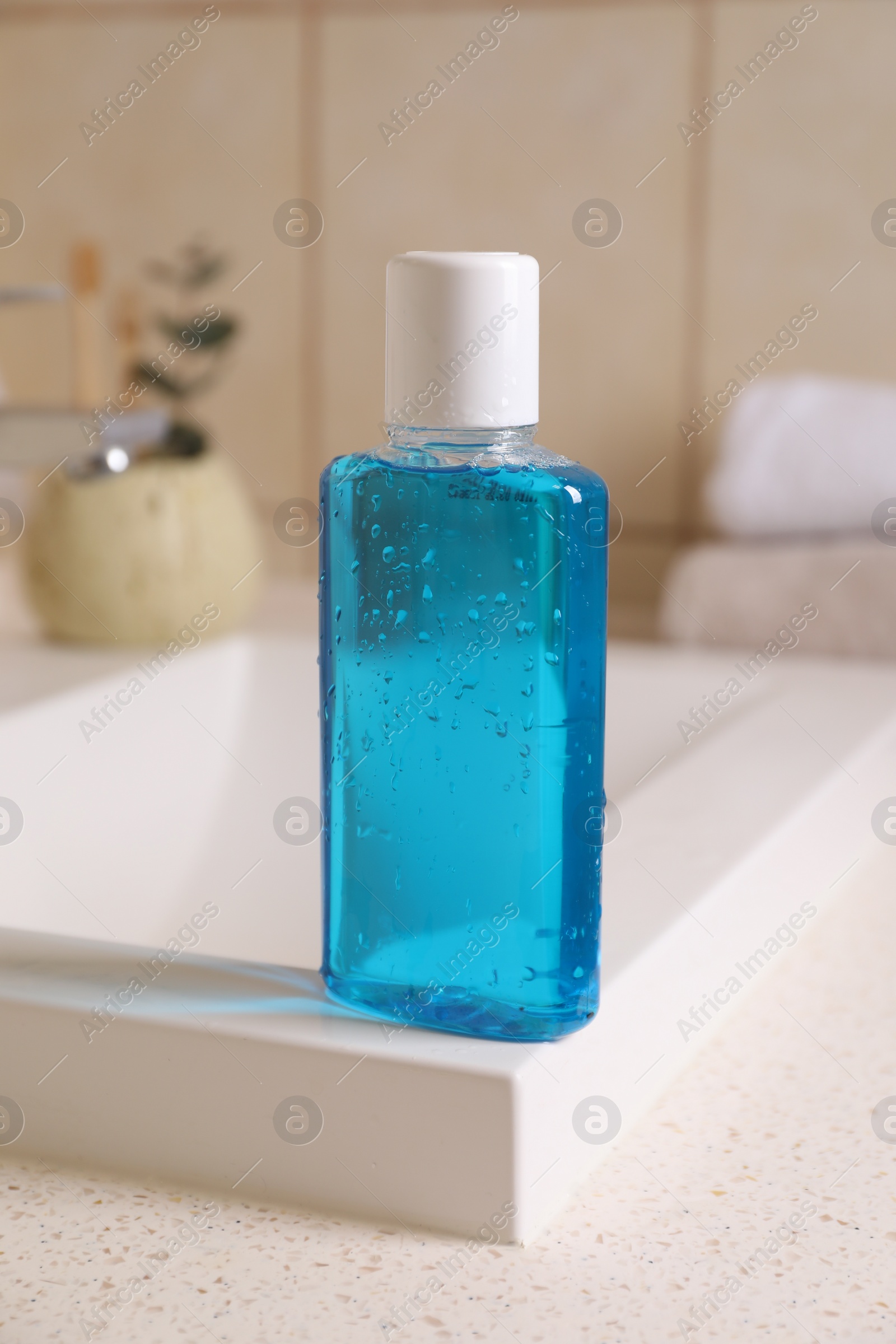 Photo of Fresh mouthwash in bottle on sink in bathroom, closeup