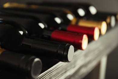 Photo of Bottles with delicious wine on shelf, closeup. Professional sommelier