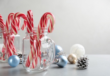 Photo of Candy canes and Christmas decor on light grey table, space for text